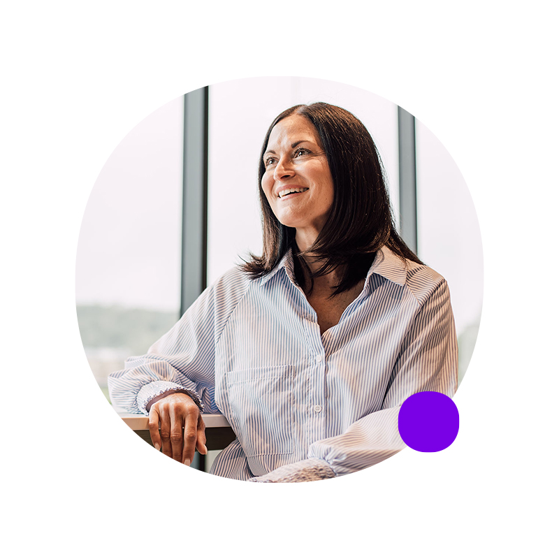 Woman in lab looking at vial through magnifying goggles