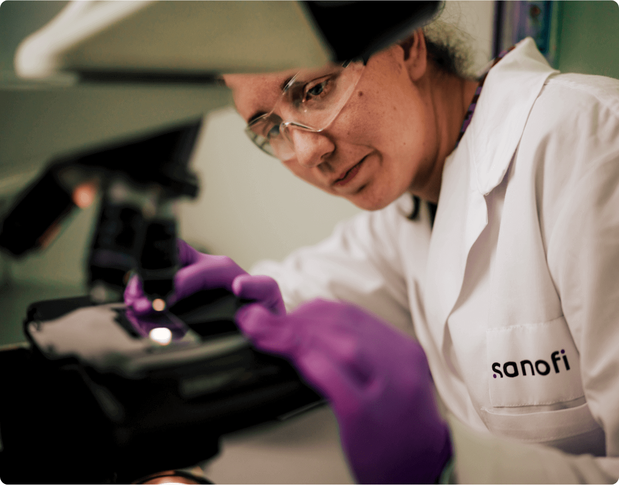 Un employé de laboratoire dans des vêtements stériles place un échantillon au microscope