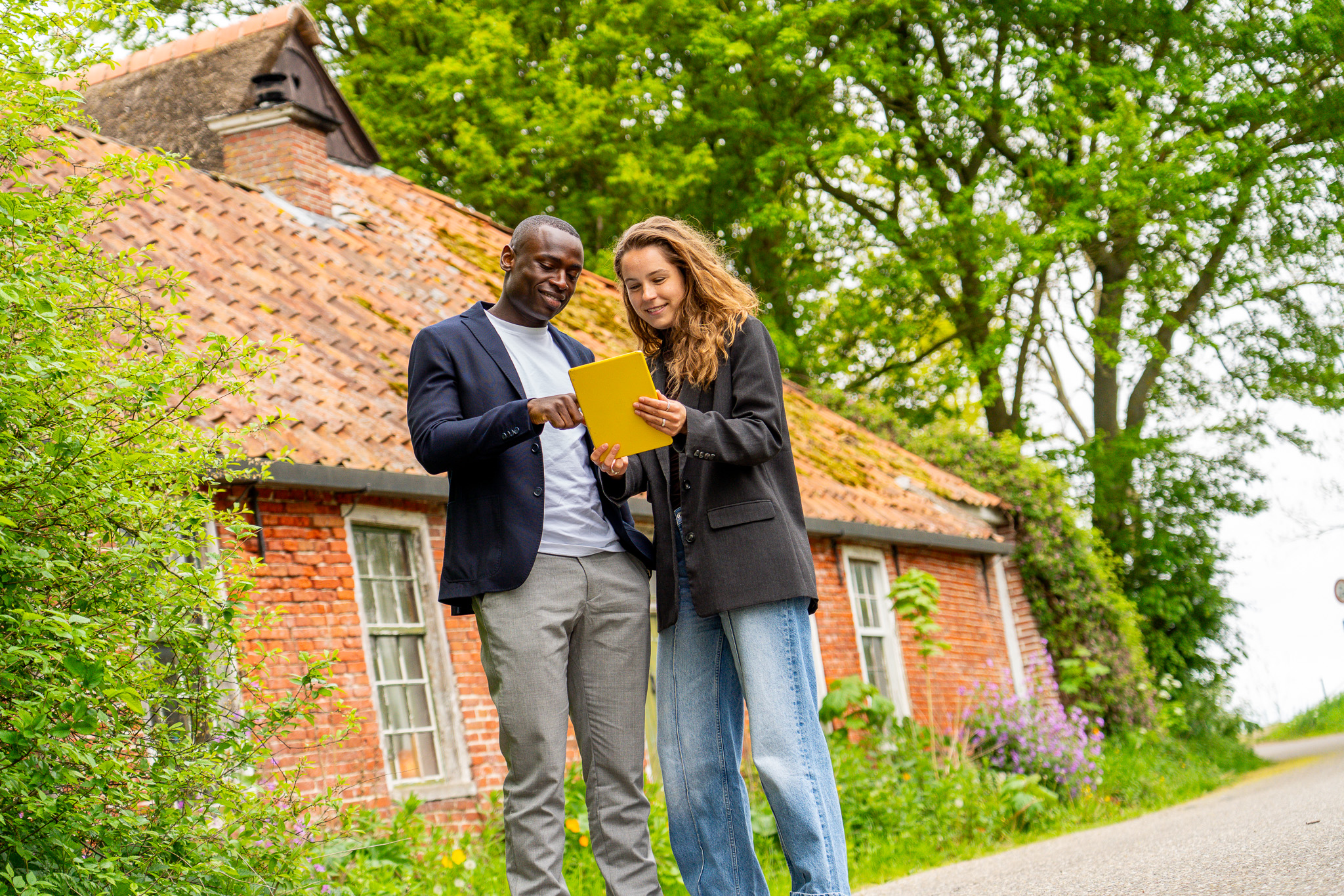 Twee Kenonz collega's met gele Ipad voor karakteristiek huis.