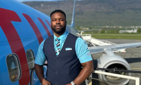 Male cabin crew stood outside aircraft with TUI plane in background