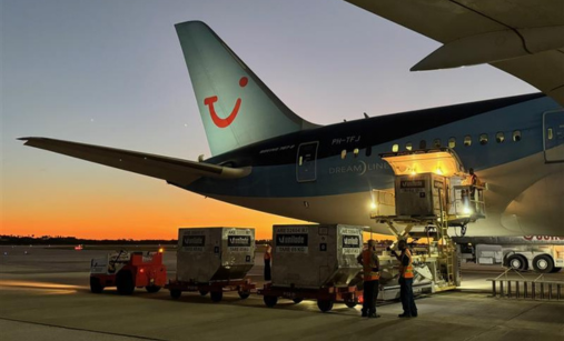 TUI aircraft with sun setting in background and luggage cart loading