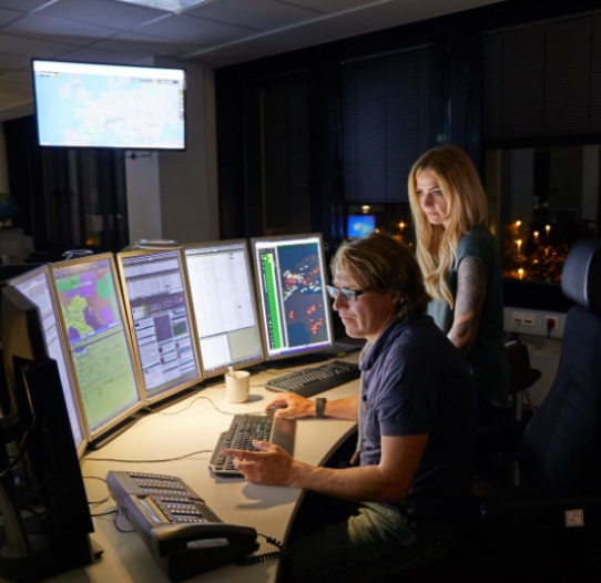 Two colleagues gathered around multiple screens in the TOCC