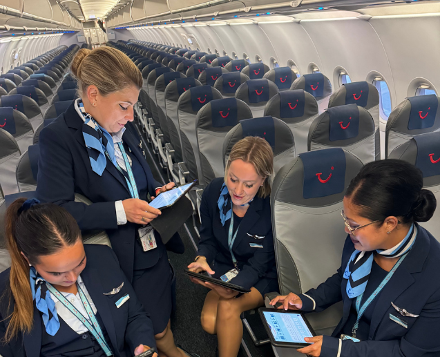 A female crew inside a plane before boarding guests looking at their iPads