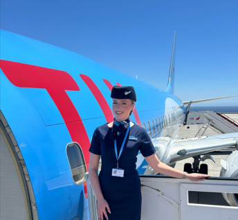 Female UK cabin crew standing outside a TUI plane at the front door