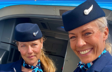 two female cabin crew taking a selfie in the door of the plane