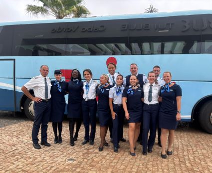 a group of TUI flight crew standing in front of a TUI bus