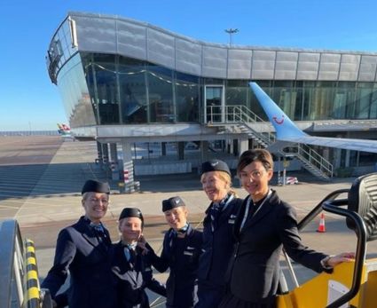 A group of TUI Cabin crew standing on a staircase next to a plane
