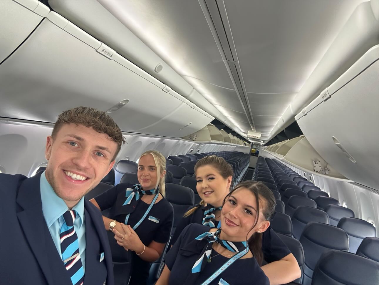 A team of young TUI Cabin Crew standing in the aisle smiling at the camera