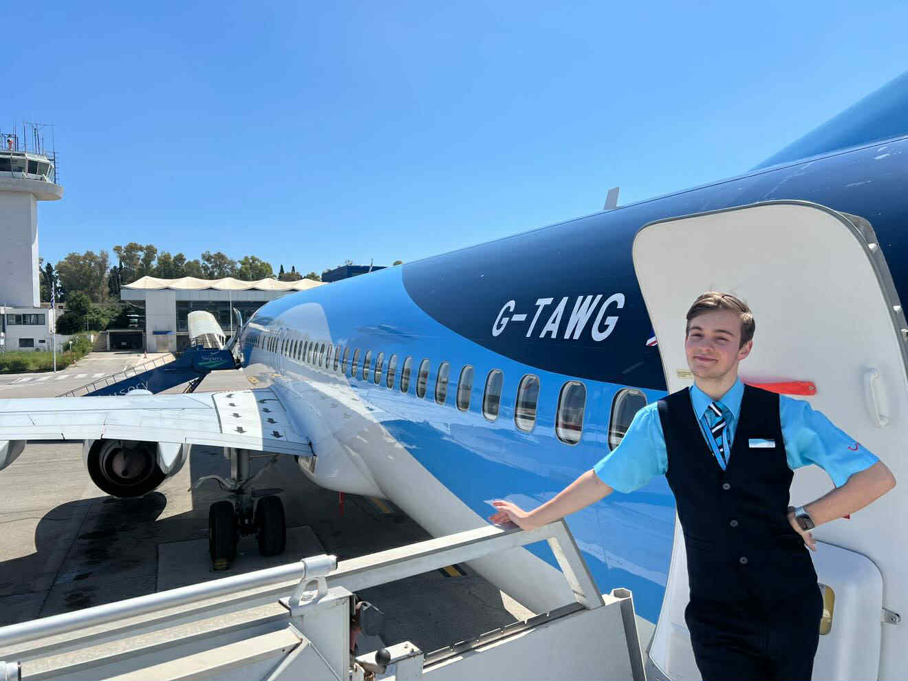 A young TUI Apprentice standing outside the door of a plane
