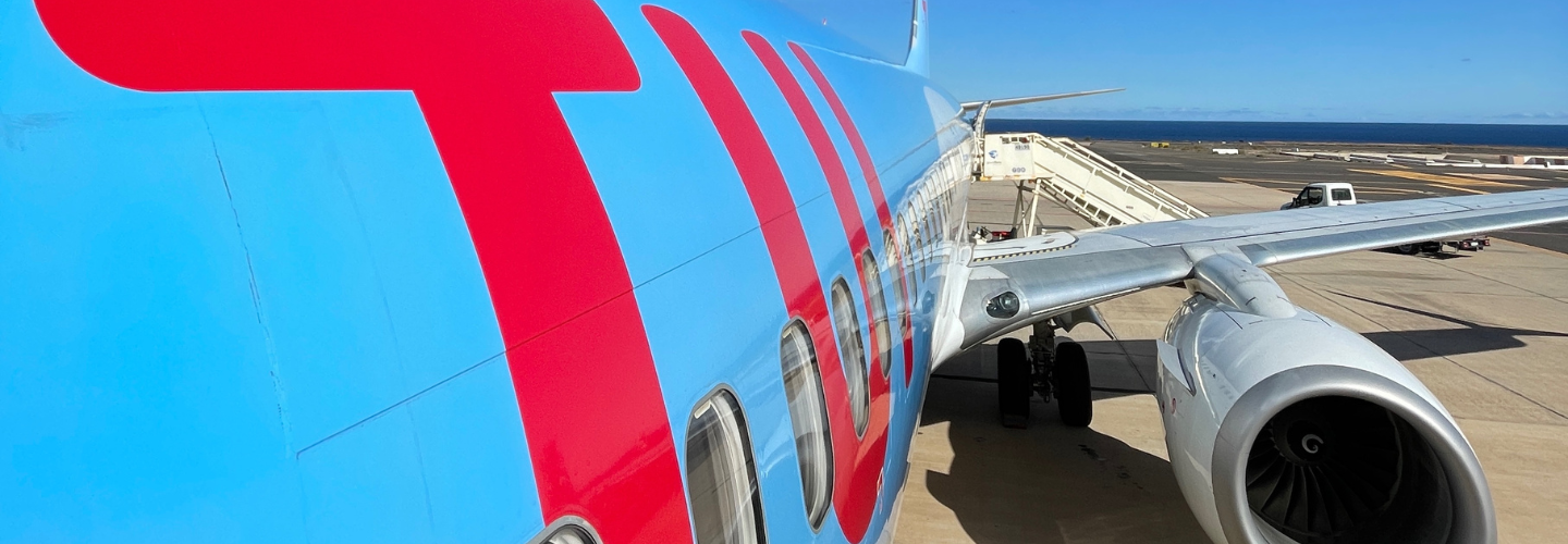 A TUI Aircraft sits at an airport with a blue sky background.