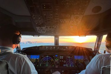Two pilots on the runway in the cockpit looking at the sunset before take off