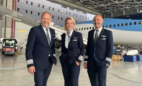 Three pilots, two male, one female, stood in the hangar in front of an aircraft