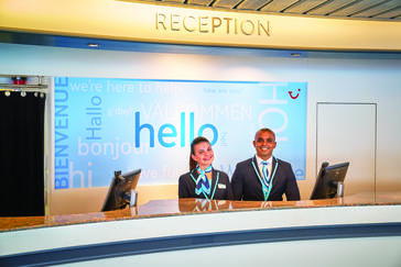 Two staff members smiling waiting for customers at the reception desk. 