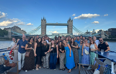 A group of colleagues smiling in front of a bridge in London. 