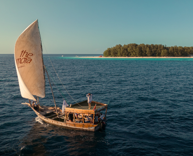 A The Mora branded sailboat floats in the ocean next to an island