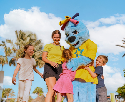 A TUI MAGIC LIFE colleague stands with three children and the TUI MAGIC LIFE mascot