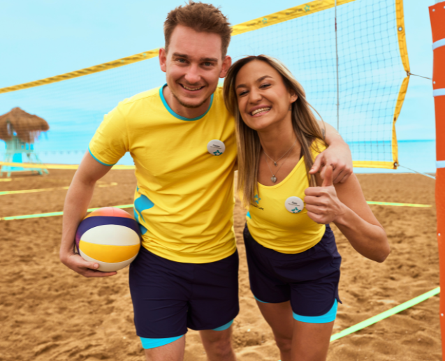 Two TUI MAGIC LIFE colleagues smile on the beach playing beach volleyball