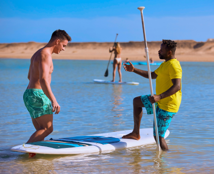 A TUI MAGIC LIFE colleague conducts a paddle boarding lesson with a guest