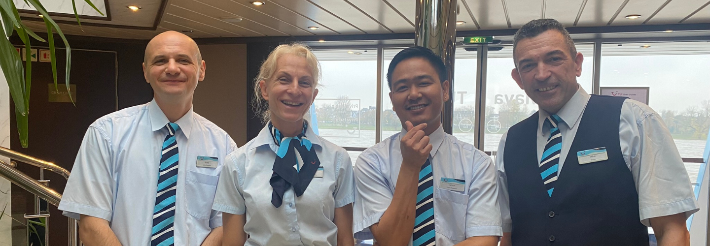A group of 4 waiters stood smiling on a TUI River Cruise ship.