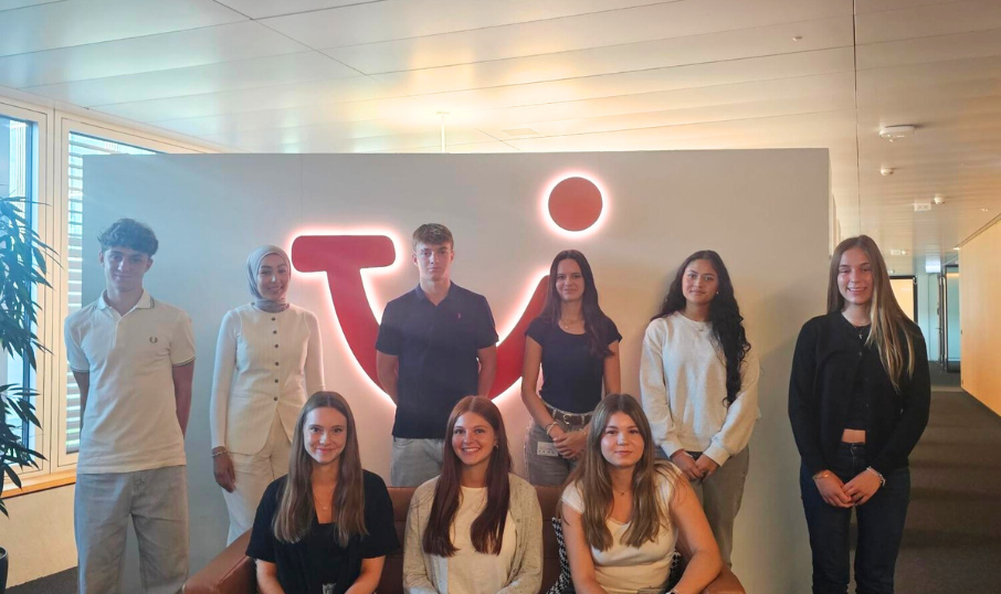 A group of young people smiling outdoors during a team moment.