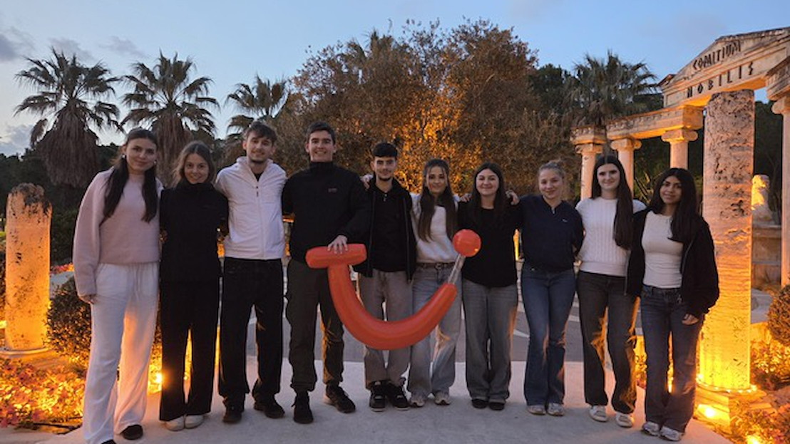 Eine Gruppe von jungen Menschen hält ein TUI Zeichen in einem Urlaubsort