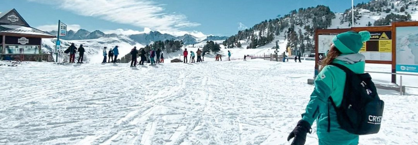 A Crystal Ski Rep in Crystal Ski uniform looks into the distance at a snowy landscape.