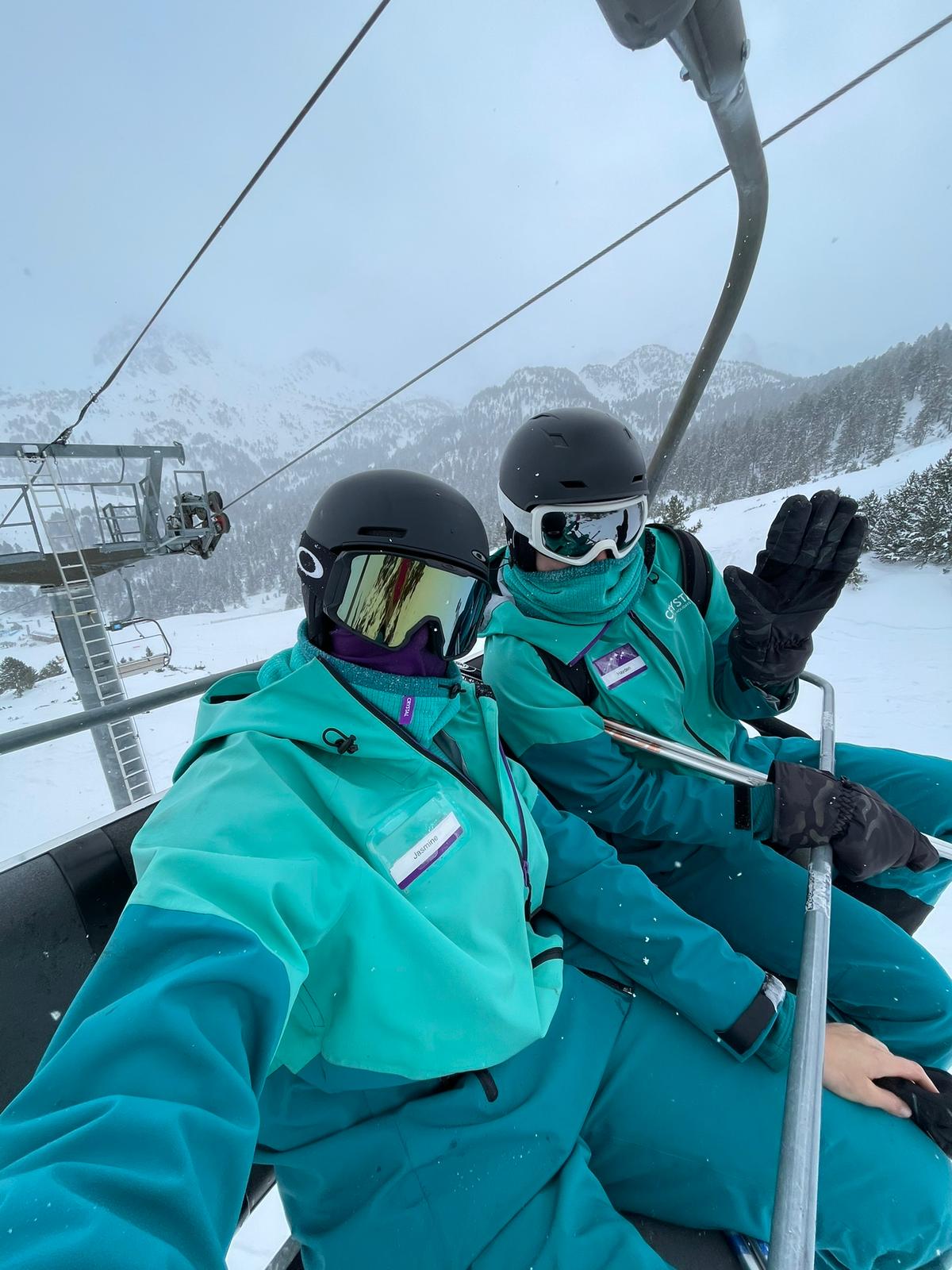 Two Crystal Ski colleagues take a selfie on a ski lift with ski masks on