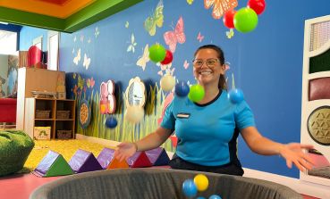 A TUI Kids Club Host throws plastic balls from a ball pit into the air in the Kids Club