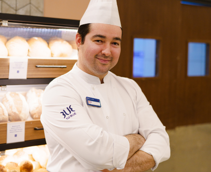 A male chef stands in front of a bread stand in a TUI BLUE restaurant.