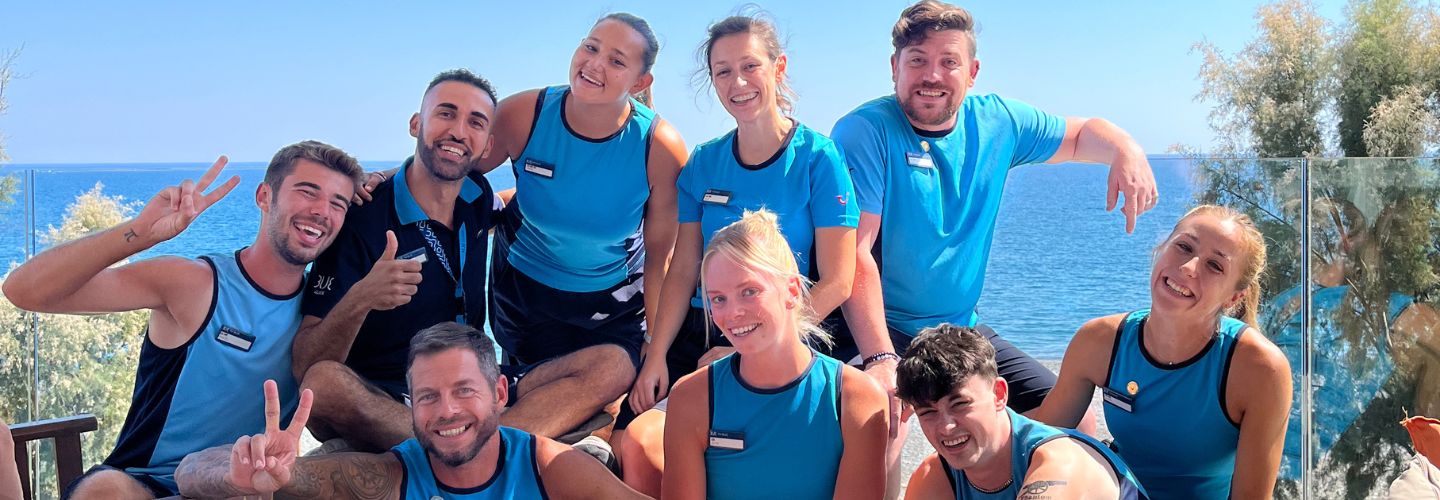 A large group of TUI BLUE colleagues pose together with a blue sky background