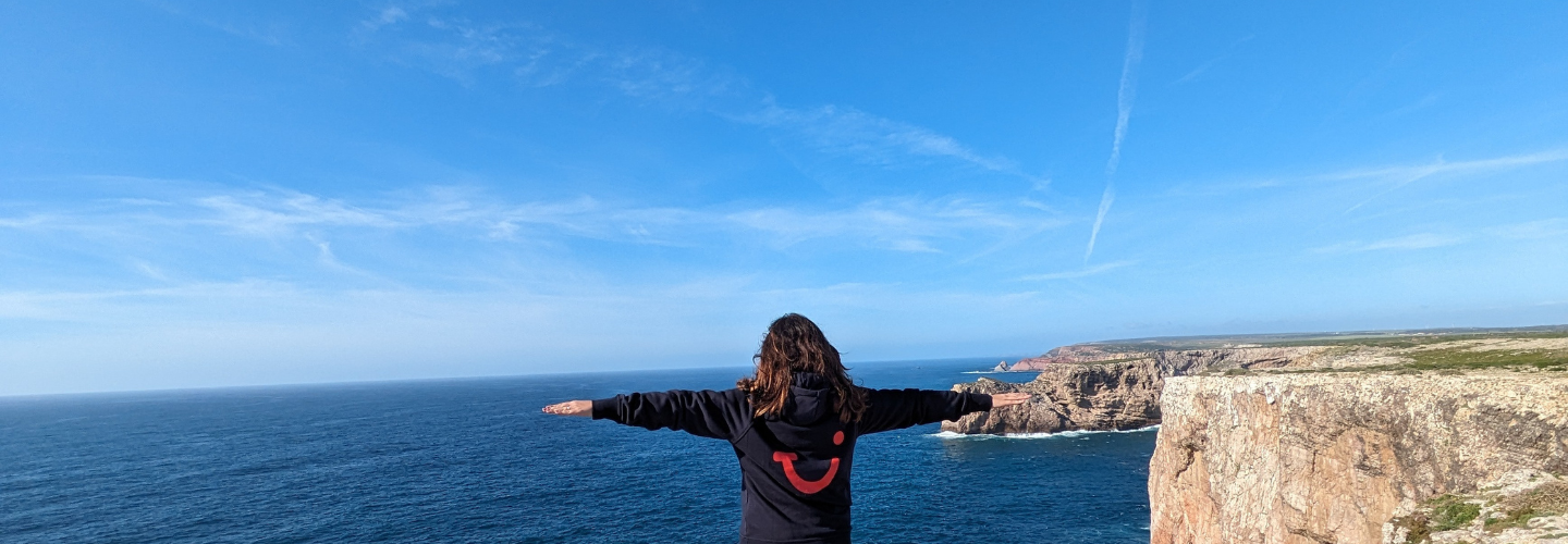 A person in a blue TUI jumper looking out at sea