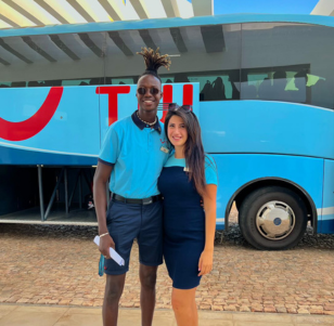 A male and female TUI Airport Rep stand in front of a large TUI transfer coach.