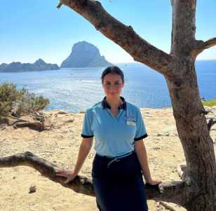 A female TUI Rep stands in front of a scenic landscape in Ibiza.