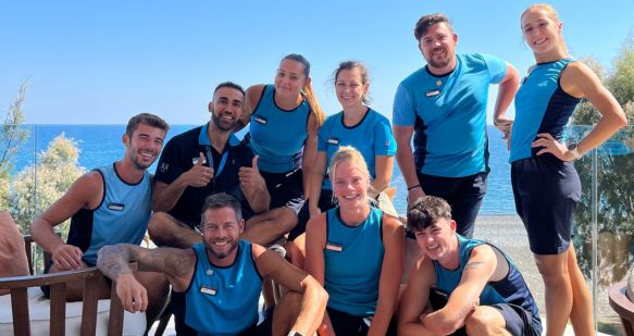 A large group of TUI colleagues smile with a blue sky background