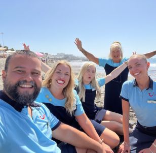 A group of TUI colleagues smile on the beach in Tenerife