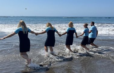 A group of TUI colleagues run into the sea in Tenerife holding hands