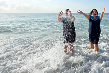 TUI employees playing in the ocean surf and laughing on a sunny day