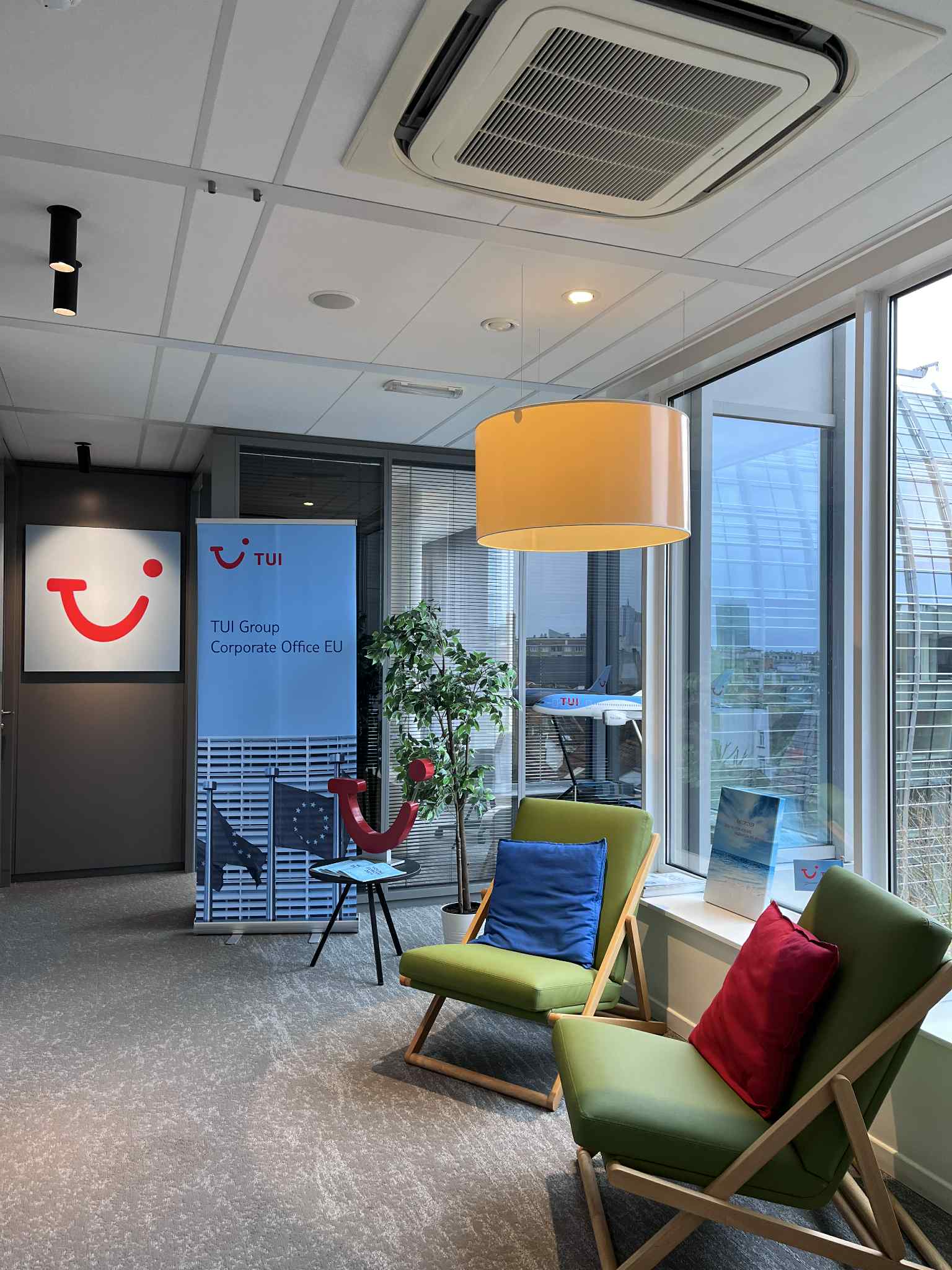 Image of an office entrance with the TUI logo and green seats to welcome guests