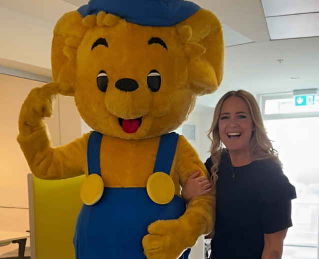 A TUI Denmark colleague stands smiling next to Bamse.