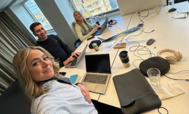 Three TUI Denmark colleagues smile in a selfie at their office desk.
