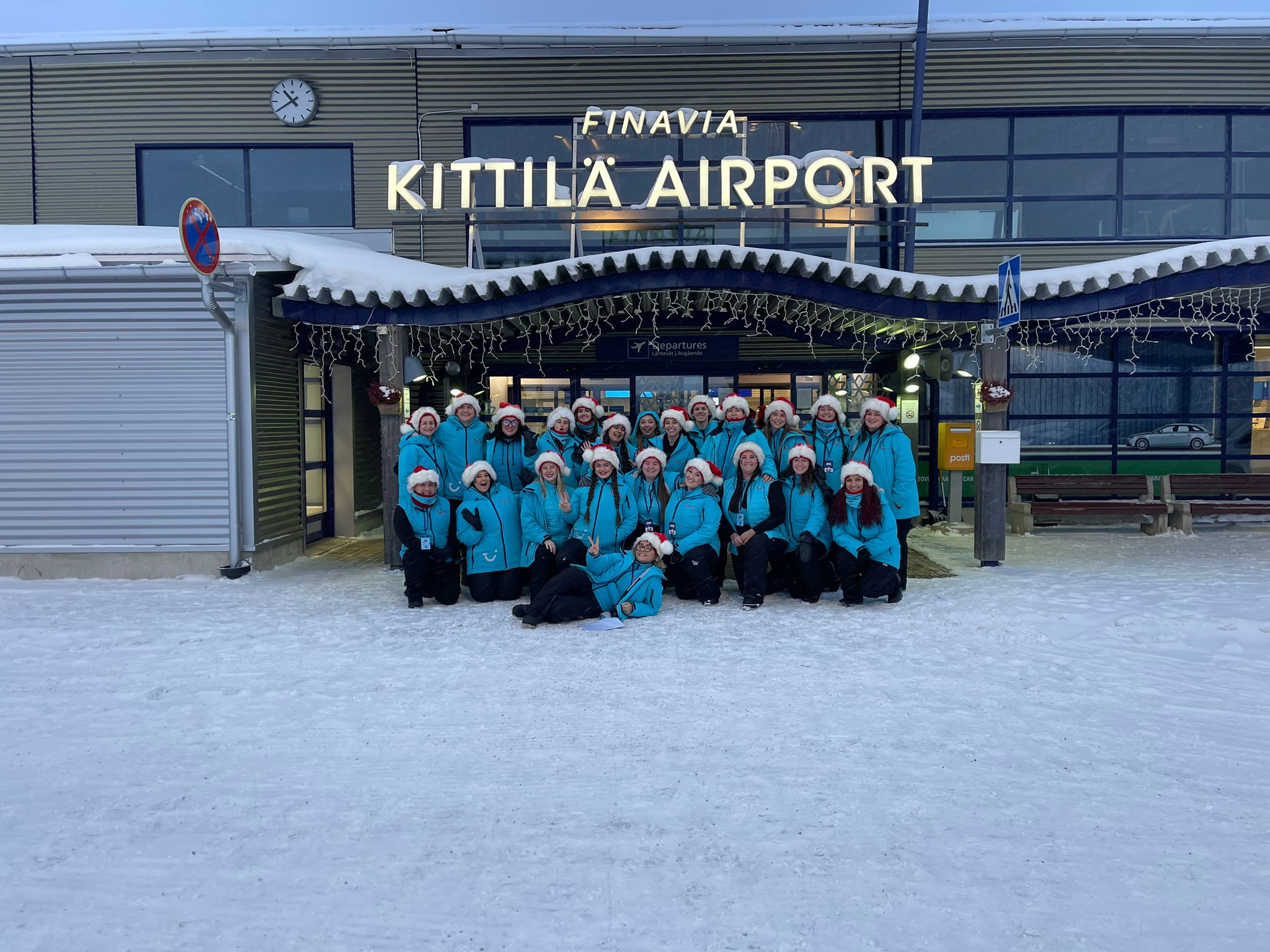 Group of people standing outside snowy Kittilä Airport in Finland.
