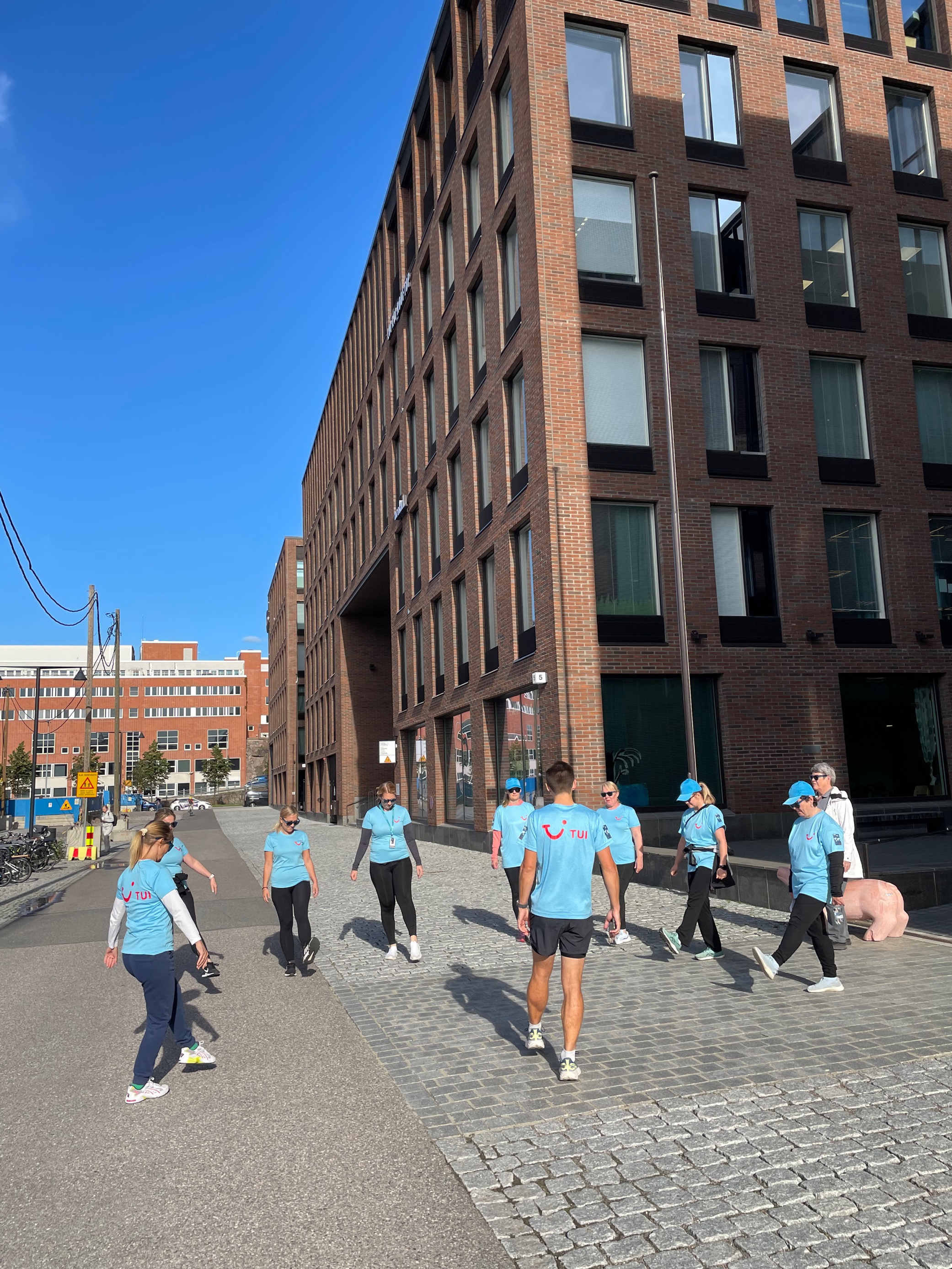 TUI colleagues standing and exercising outside the Finland office on a sunny day.