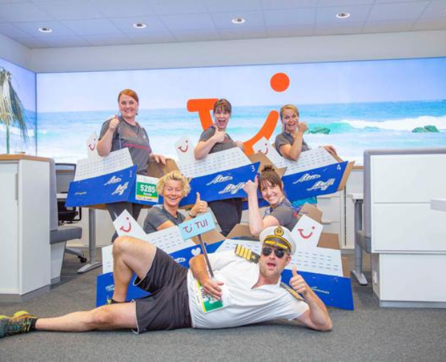 A group of a man and woman are in a TUI Retail Store they smile into the camera and have martime themed fun heads on