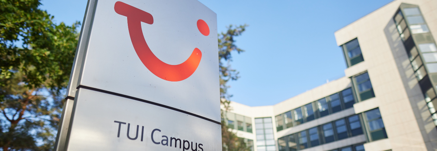 A pilar with the TUI Smile Logo it says written TUI Campus. In the background is a building