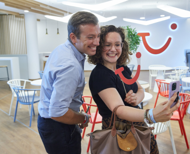 Two people take a selfie smiling at the camera. They have TUI merchandise