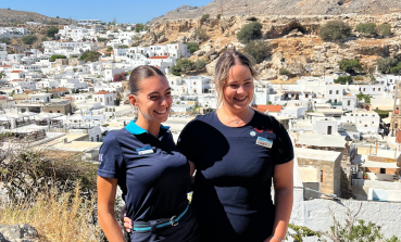 Two TUI Greece colleagues stand with Lindos in the background