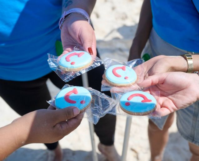TUI colleagues hold TUI themed biscuits on a Mexico beach
