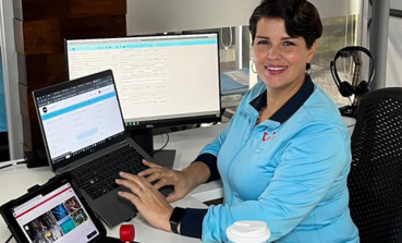A TUI Mexico colleague sits at her desk with a laptop, tablet, and desktop in front of her