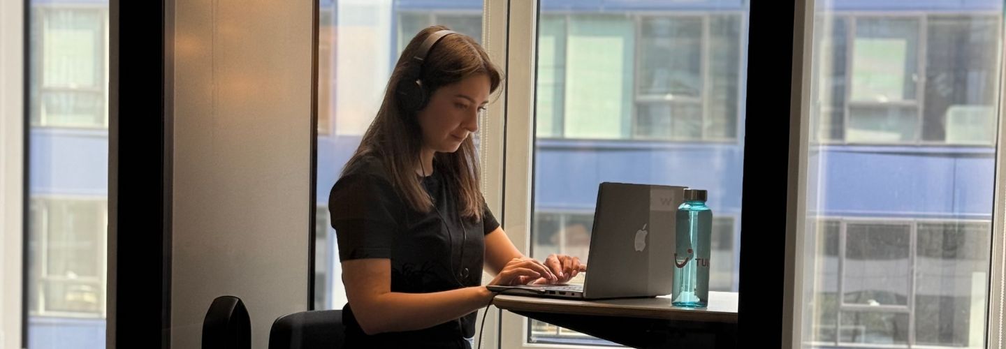 A TUI Poland sits at their work desk with a TUI bottle and laptop