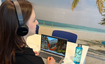 A TUI Poland colleague sits at her laptop with her headset on